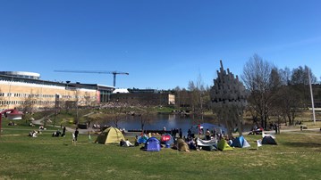 Tält placerade på gräset framför dammen på Campus Umeå.