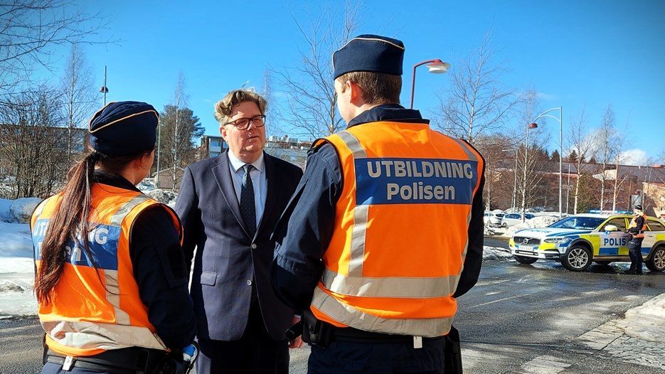 Justitieminister Gunnar Strömmer står mellan två polisstudenter