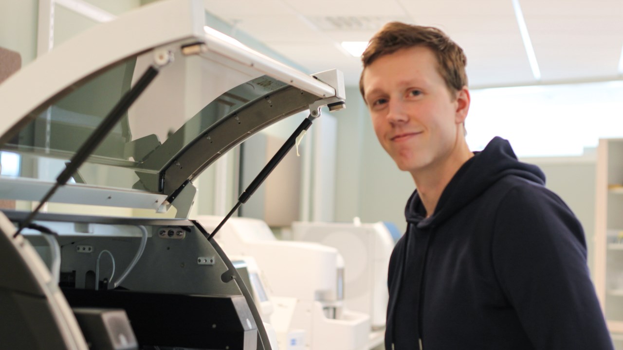 Pontus Blom stående framför ett mätinstrument på företaget Nordic Biomarker.