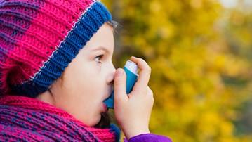 Astmasjukt barn inhalerar astmamedicin.