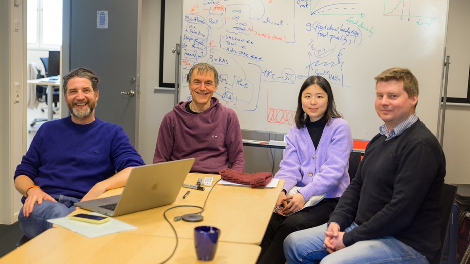Olivier Keech, Sebastian Diehl, Yun-Ting Jang and Jonas Westin sit at a conference table and smile at the camera. Behind them is a whiteboard with project plans sketched out. 