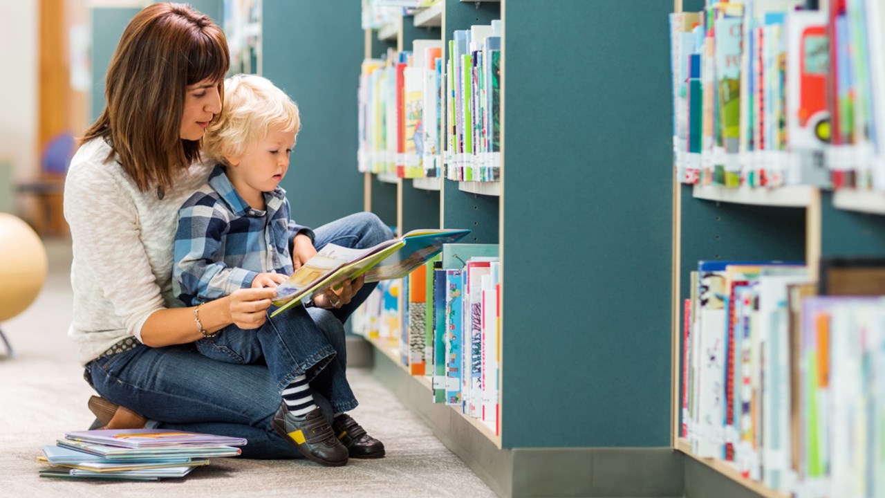 Förskolebarn med vuxen i bibliotek.