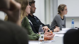 Flera idéhistoriestudenter sitter vid ett bord och lyssnar vid ett seminarium