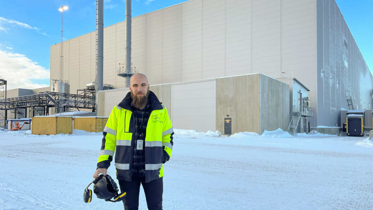 Bild på Jonathan Mellåker framför Northvolts fabrik i Skellefteå