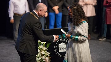 The Vice-Chancellor  hands over a congratulatory scroll to a graduating master's student at Umeå University.