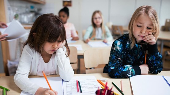 Lågstadieflickor jobbar i klassrum.