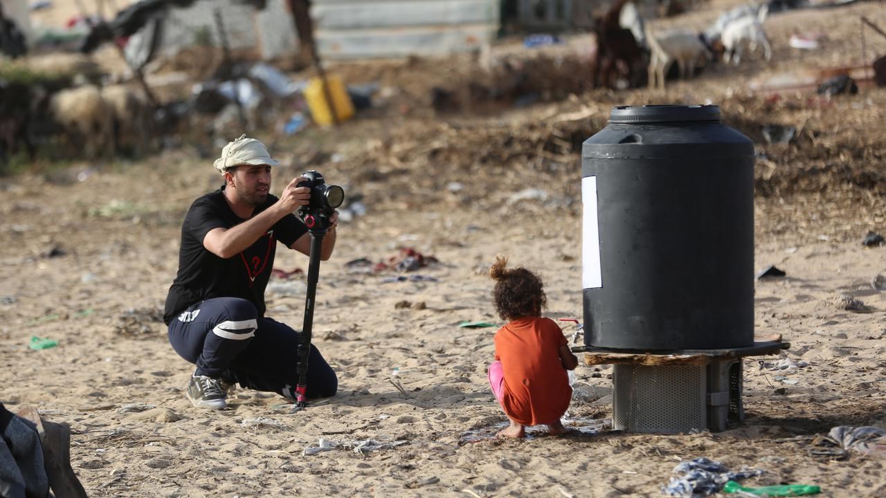 En man som fotograferar en liten flicka på stranden.