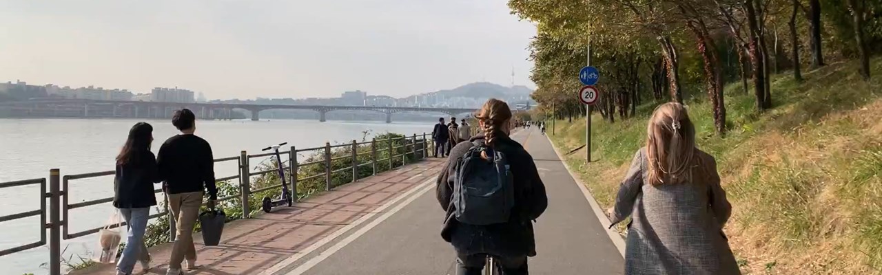 Två studenter cyklar på en cykelväg längs en flod i Sydkorea