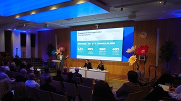 En grupp människor som sitter i stolar framför en projektorduk.