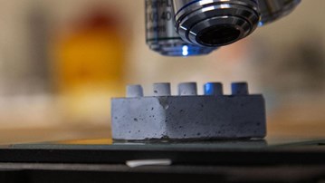 En legobit i cement under ett mikroskop