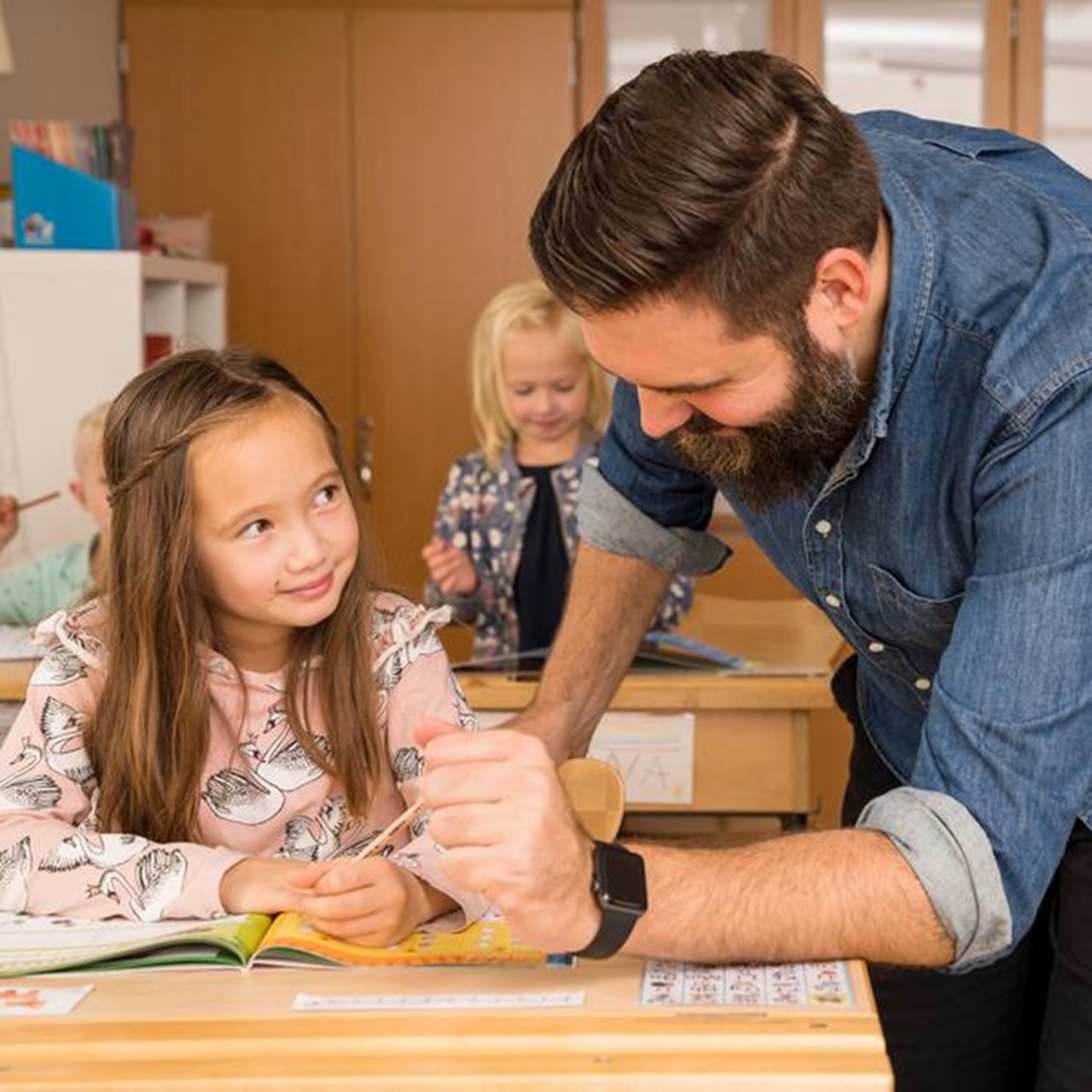 Lärare hjälper en elev vid hennes skolbänk.