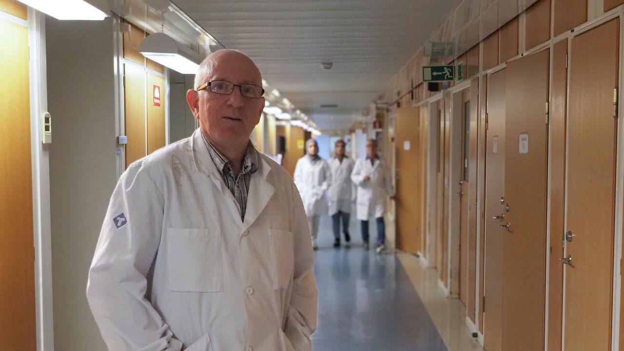 En man i labbrock som st&aring;r i en korridor.