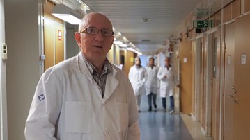 En man i labbrock som står i en korridor.