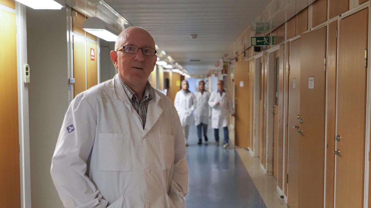 En man i labbrock som står i en korridor.