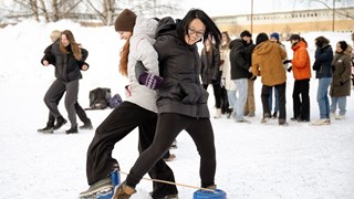 Två personer står rygg mot rygg i armkrok i en lek.