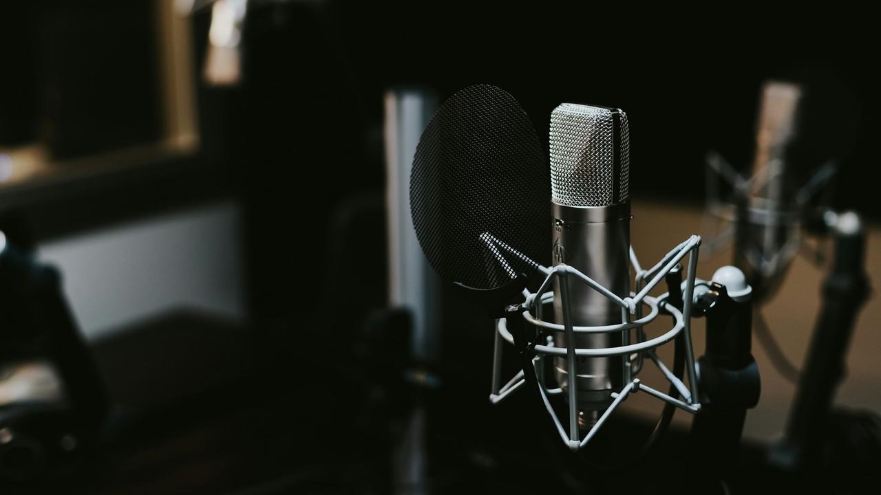 En podcaststudio med en mikrofon i ett mörkt rum.