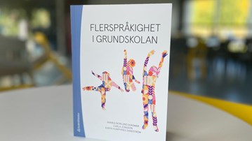 Boken Flerspråkighet i grundskolan står på ett runt bord.