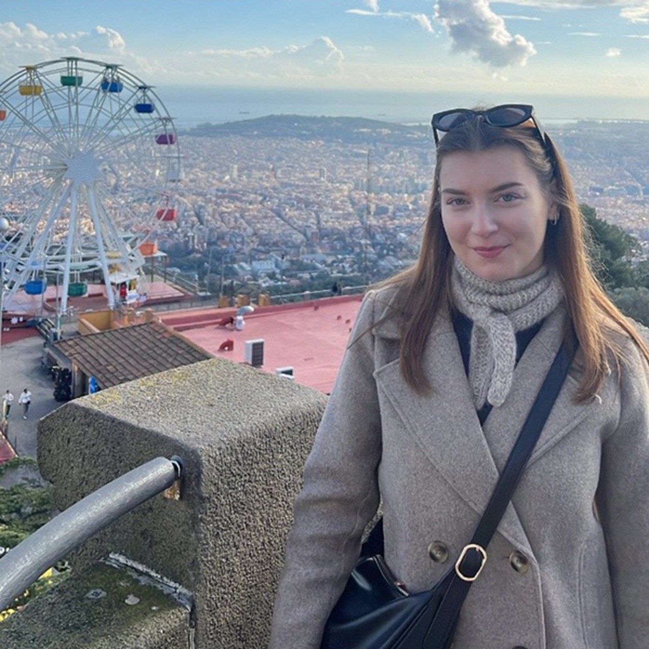 Kvinna i förgrunden med en stad och ett pariserhjul i bakgrunden.