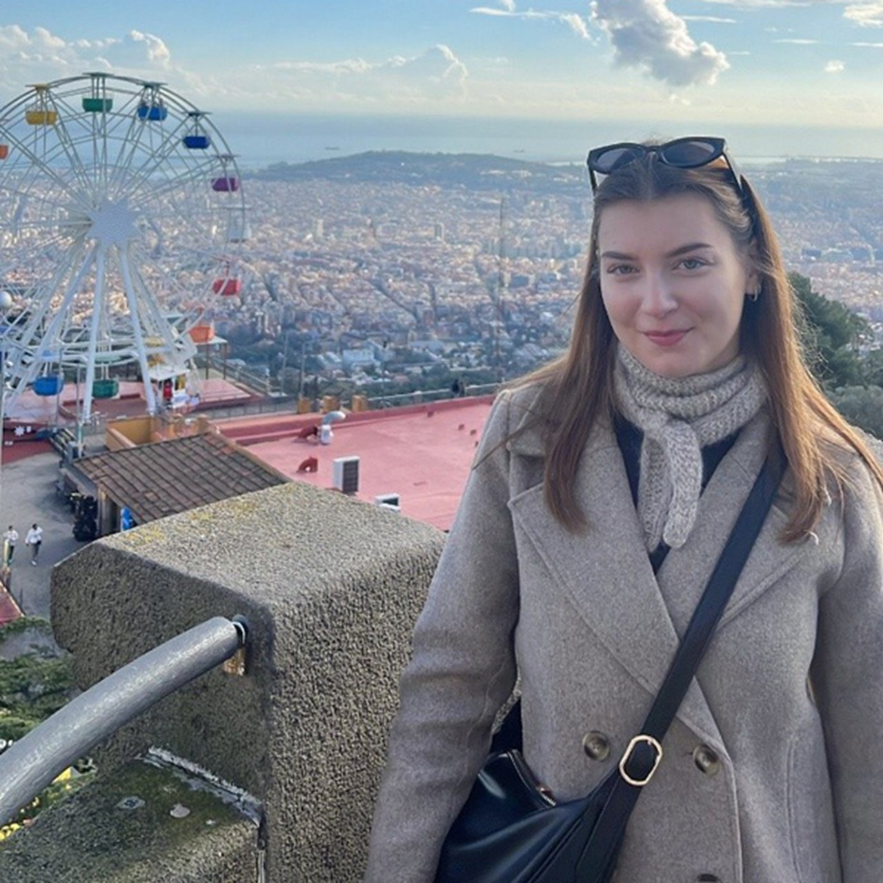 Kvinna i förgrunden med en stad och ett pariserhjul i bakgrunden.