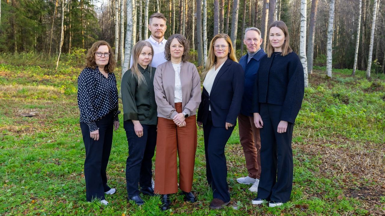 En grupp m&auml;nniskor som st&aring;r bredvid varandra i en skog.