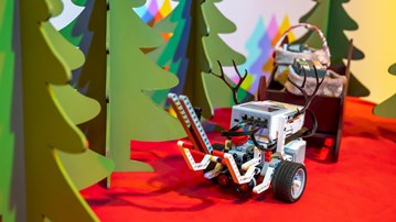 En EV3-robot med renhorn kör släde med julklappar bland granar