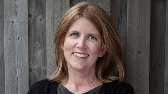 Sara Viklund står framför en trävägg.