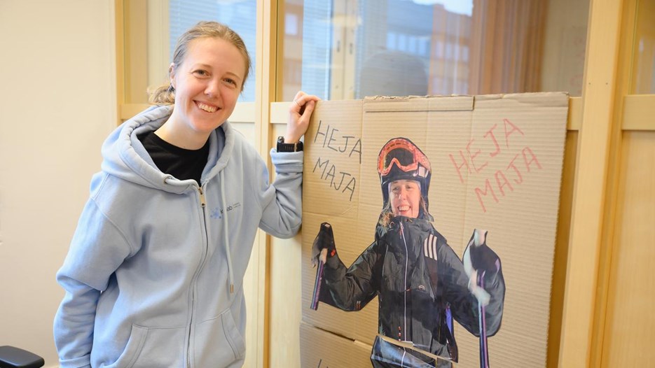 A woman standing next to a poster of herself skiing.