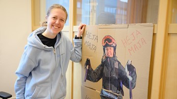 A woman standing next to a poster of herself skiing.