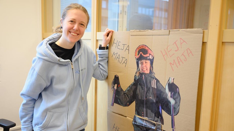 A woman standing next to a poster of herself skiing.