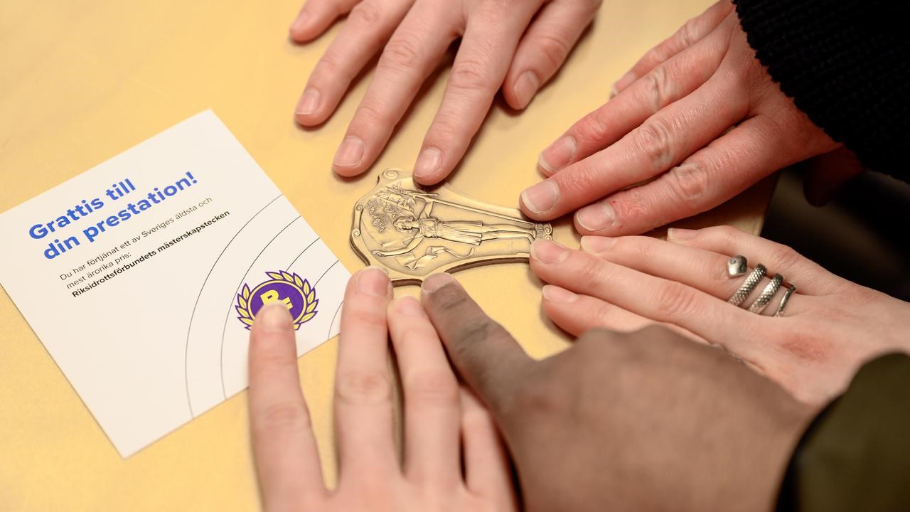 A group of people touching a bronze medal.