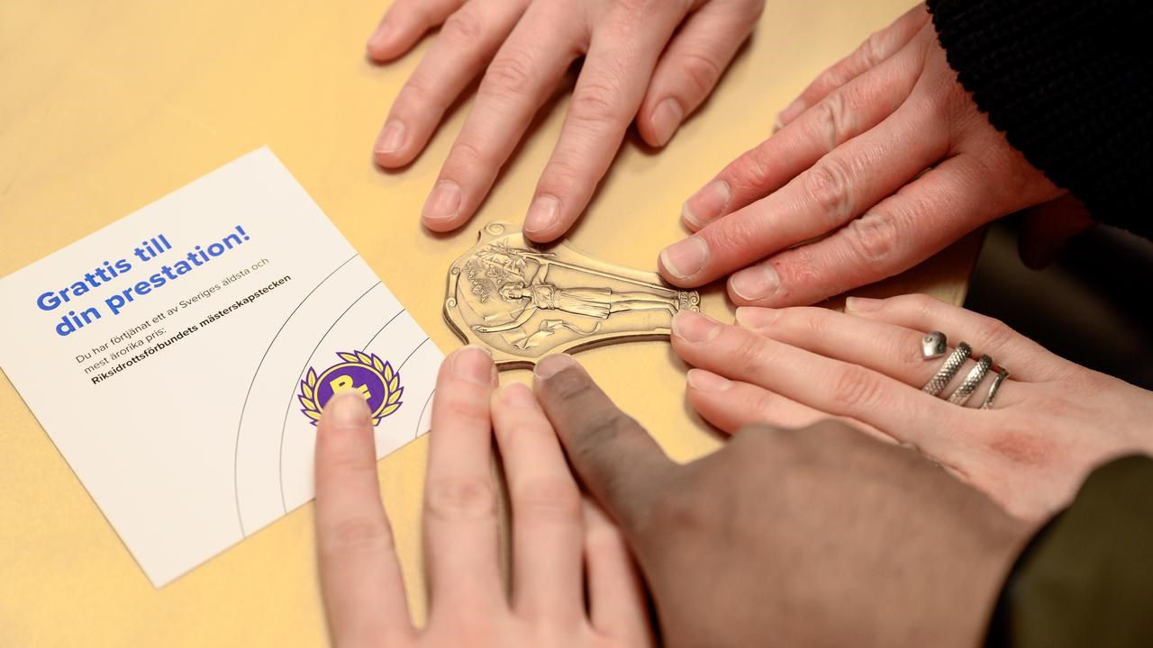 A group of people touching a bronze medal.