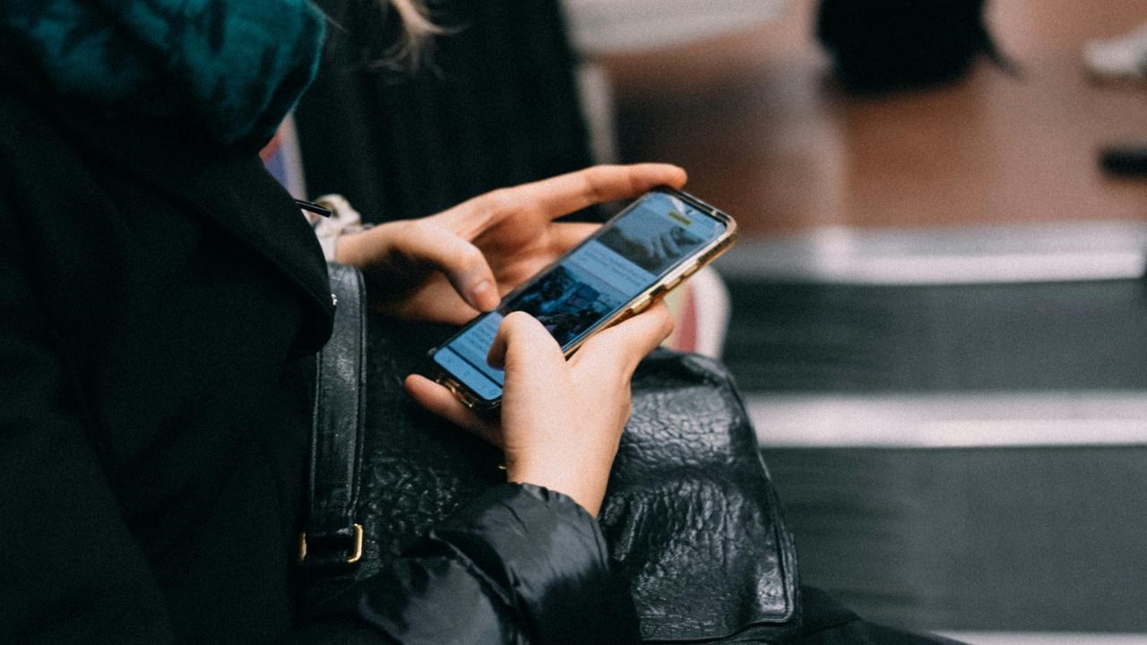 En person som sitter på en bänk och pratar i mobiltelefon.