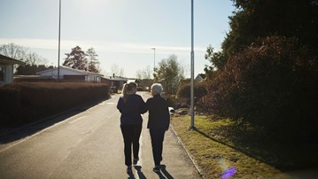 Äldre och yngre kvinna promenerar bort från fotografen