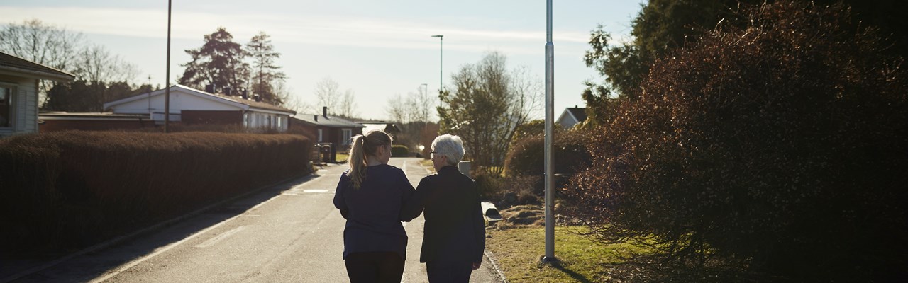 Äldre och yngre kvinna promenerar bort från fotografen