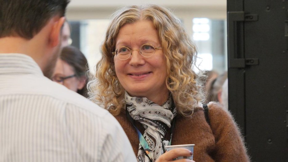 Två deltagare pratar med varandra. En har en kaffekopp i handen-