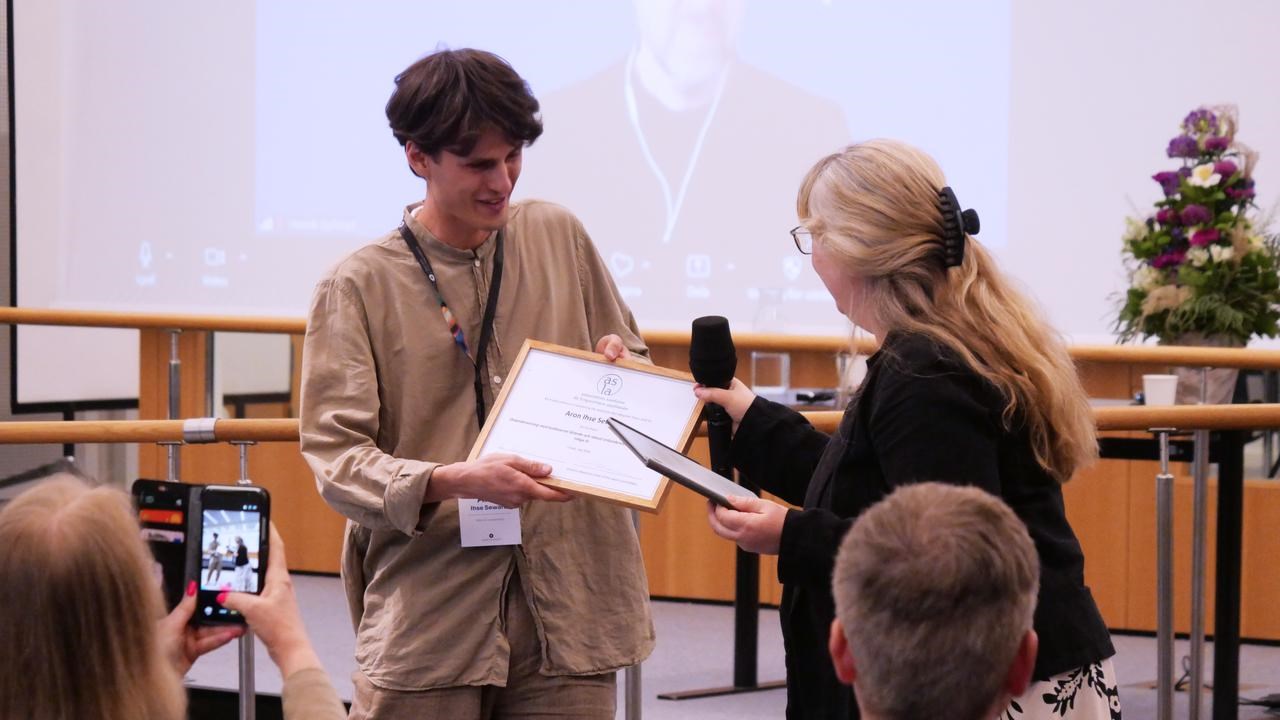 Tar emot pris för bästa studentuppsats.