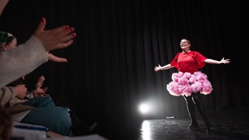 Emelie står på en scen med en rosa fluffig kjol.