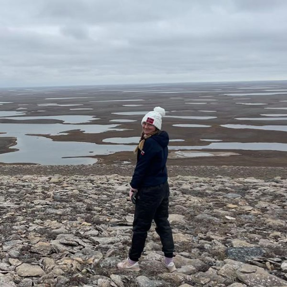 Lena Leimgruber Haraldsson stands on stony ground with open views behind her.