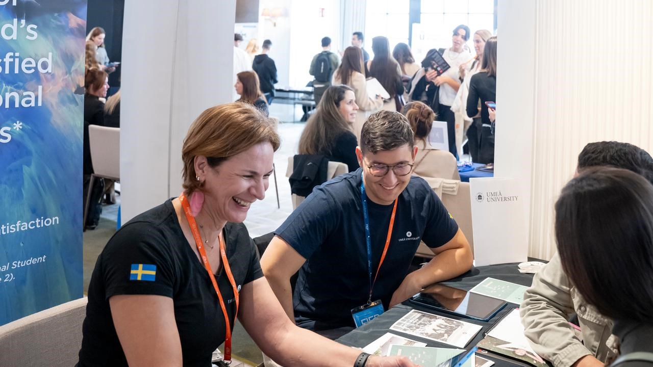 Umeå University's representative talking to prospective students at an education fair.