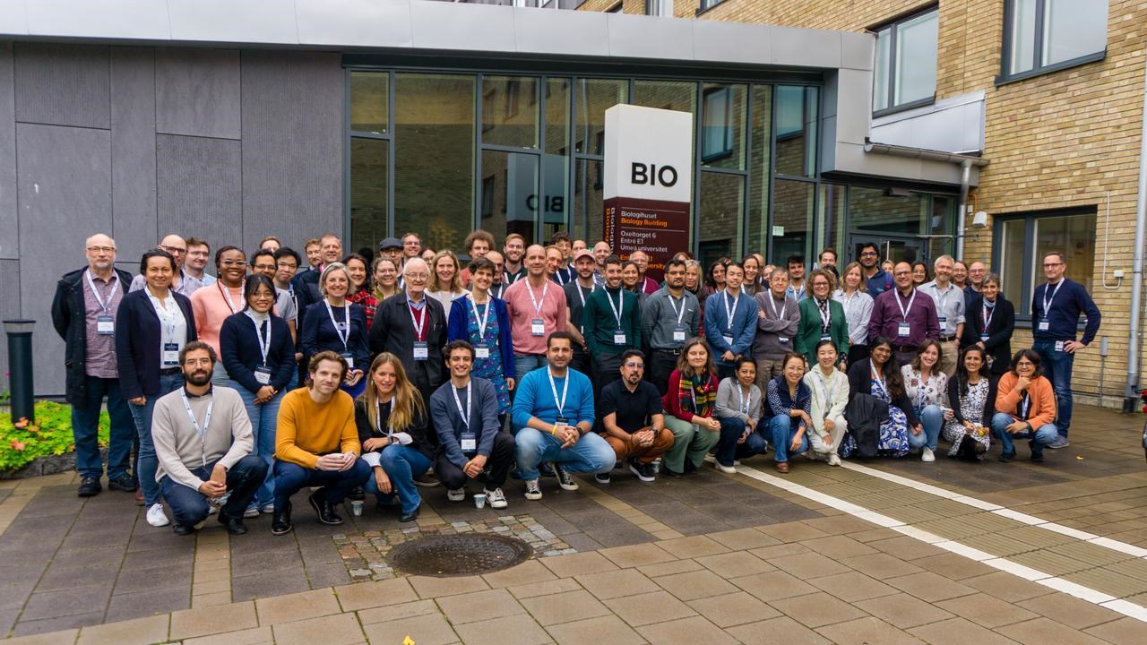 En stor grupp symposiumdeltagare poserar tillsammans utanf&ouml;r Biologihuset vid Ume&aring; universitet.
