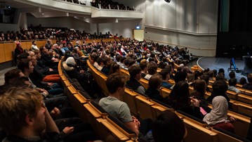 En man talar för en en fullsatt aula