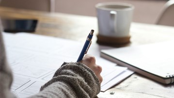 En arm som håller i en penna och skriver anteckningar