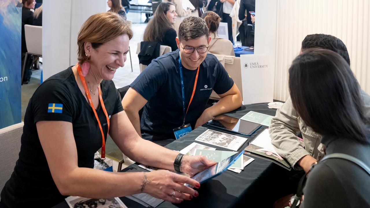 Representatives from Umeå University in a student fair, talking to prospective students.