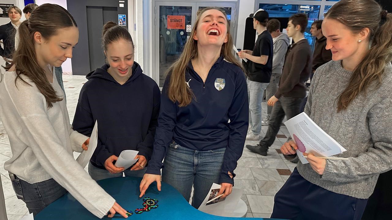 Fyra unga kvinnor deltar i semifinalen av Unga forskare, som arrangerades i Umeå den 28 februari. De står runt ett blått bord och interagerar med färgglada knutar, rep och informationsblad.