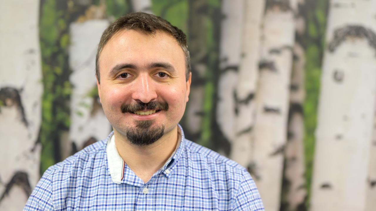 A man with a mustache standing in front of a painting