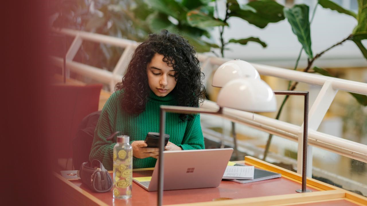 Studenten Sarah pluggar med dator och anteckningsblock.