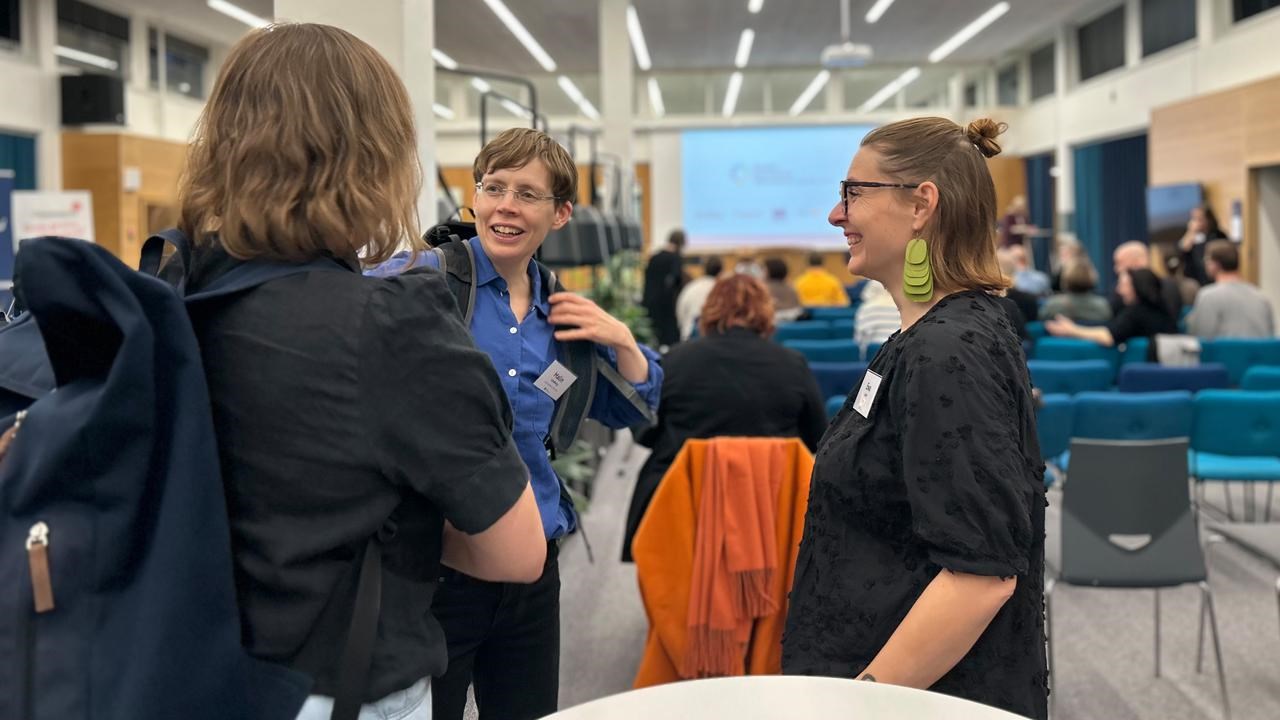 En grupp m&auml;nniskor som pratar i en konferenslokal.