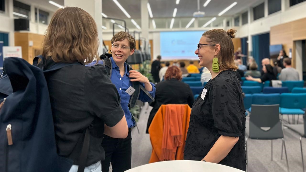 En grupp m&auml;nniskor som pratar i en konferenslokal.