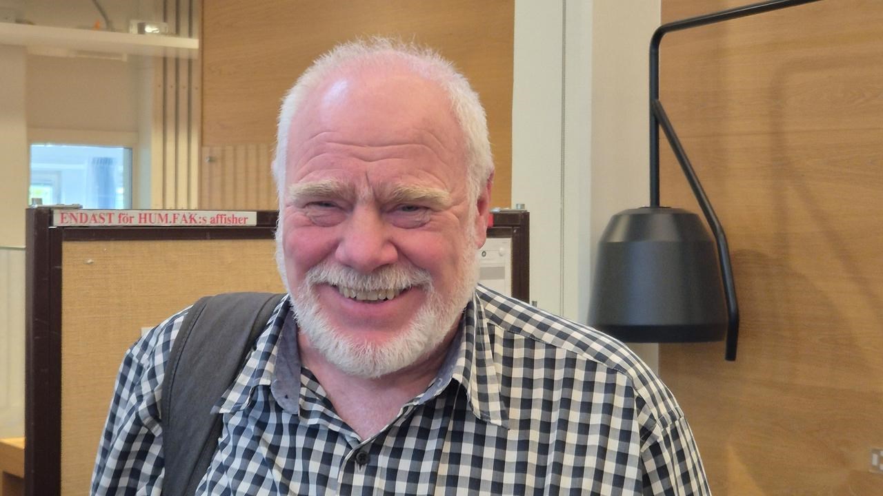 &Auml;ldre man ler mot kameran i konferenslokal.