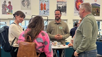 Grupp av människor samtalar vid ett ståbord i konferenslokal.